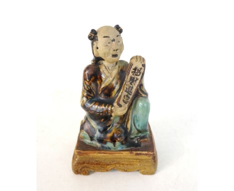 CHINESE GLAZED POTTERY FIGURE OF A SCHOLAR
holding a character scroll and in kneeling position, with provision for brush, rai