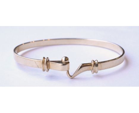 NINE CARAT GOLD BANGLE
of decorative hook and clasp design, approximately 13.3 grams
