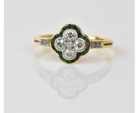An early 20th century 18ct yellow gold emerald and diamond ring, the quatrefoil raised platform set with five diamonds within
