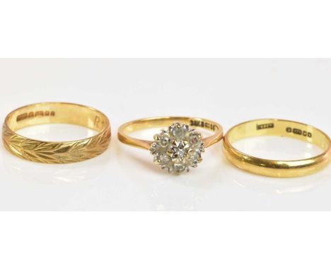 A 9ct yellow gold wedding band, size M, a further 9ct gold band ring, size K 1/2, and a 9ct gold floral set ring, size M, com