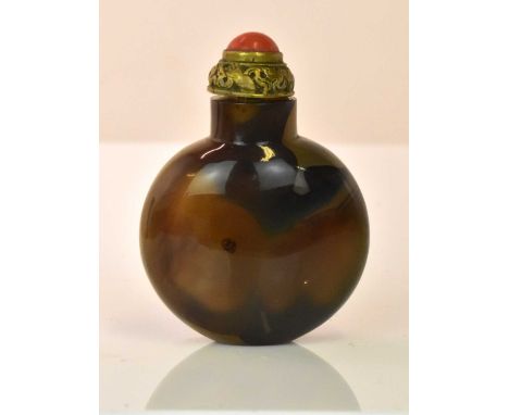 A Chinese carved agate snuff bottle of ovoid form, with spoon attached to the scroll decorated lid set with a coral cabochon,