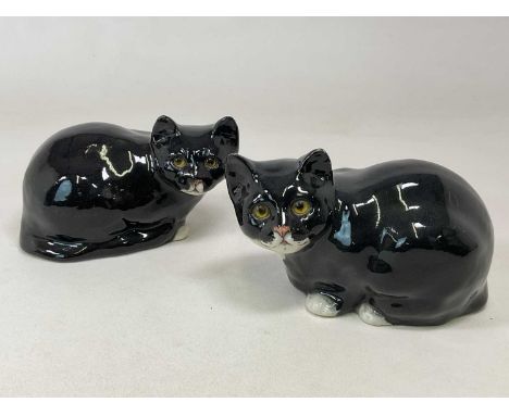 WINSTANLEY POTTERY; a pair of seated black and white cats, height 17cm, width 26cm. (2)