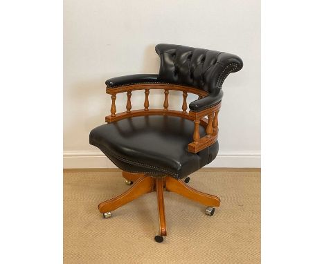 A button leather upholstered and spindle back wooden framed captain's tub chair on castors.
