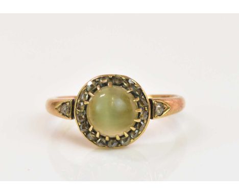 A yellow metal moonstone and diamond ring, the moonstone cabochon set within a frame of diamond chips, size J 1/2, approx 2.8