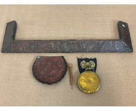 An Arts and Crafts beaten copper fire curb, an Art Nouveau beaten copper crumb tray and a brass gong on elephant mask shield 