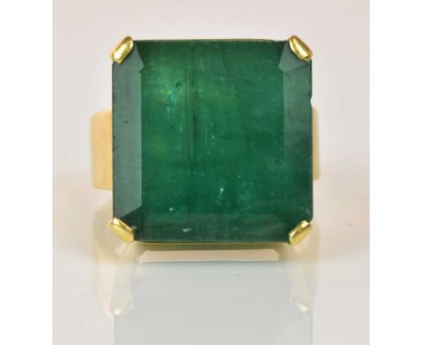 An impressive 18ct yellow gold and Colombian emerald ring, the rectangular cut stone weighing approx 25ct with four simple co
