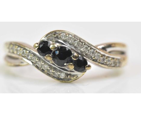 A 9ct white gold ring of swept design centred with three dark sapphires, size N 1/2, approx 2.60g.