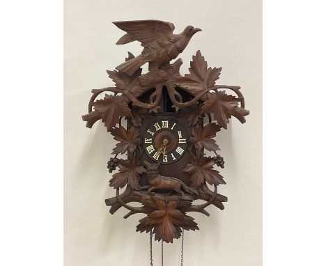 A well carved and large late 19th century Black Forest cuckoo clock surmounted with a bird above a running fox, with three pi