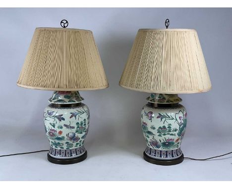 A pair of Chinese hand painted ceramic table lamps with brass collar and bases, with pleated cream shades, height excluding f