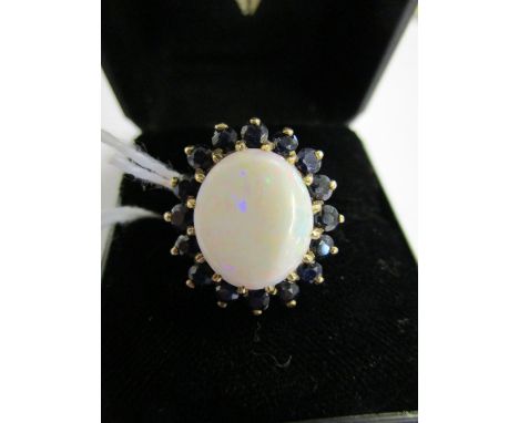 A 9ct gold opal and sapphire cluster ring, the large round opal surrounded by sixteen sapphires, 5.8g 