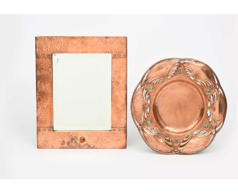 A Jugendstil copper and brass wall mirror, rectangular with stud decoration, set with brass panel and red enamel roundel, and