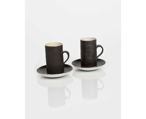 Φ Dame Lucie Rie DBE (1902-1995)a pair of stoneware coffee cups and saucers, cylindrical with loop handle, covered in a manga