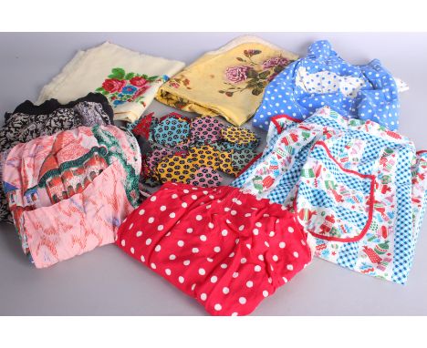 A quantity of textiles, embroidered items, a floral tea-cosy, table cloths, napkins, aprons, patchwork pieces and similar ite