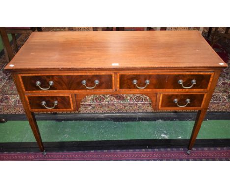 An Edwardian mahogany writing table, crossbanded rectangular top above an arrangement of drawers, tapered square legs, caster