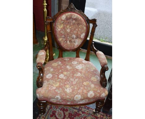 A Victorian mahogany open armchair, deep button oval back flanked by fluted foliate capped supports, bowed arms applied with 