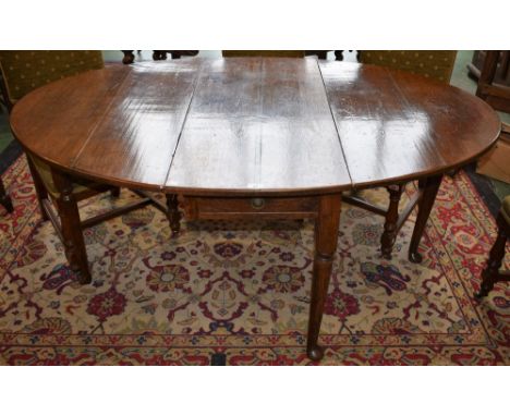 An 18th century oak drop leaf dining table, elliptical top with fall leaves above a single frieze drawer, straightened cabrio