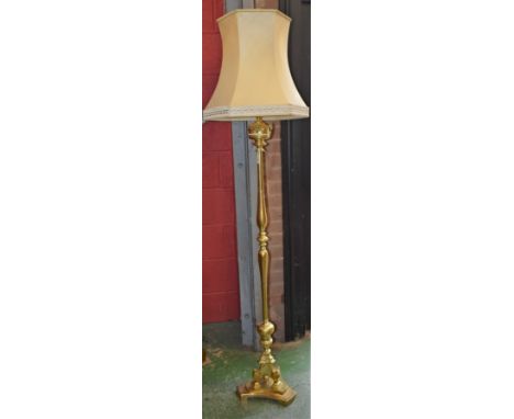 A brass standard lamp, the imitation font applied with cherub masks, triform base