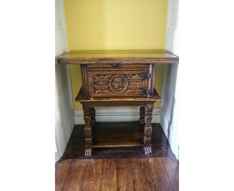 An early 20th century monk's bench/hall table, with folding top above a carved cupboard door with carved leg, 83cm high x 91c