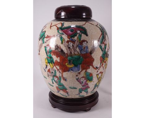 A Chinese crackle glaze ginger jar with polychrome enamel decorated battle scenes, set on a wooden cover and on a similar bas