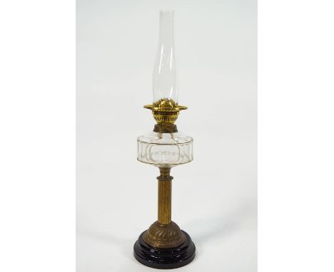 A brass oil lamp with cut glass reservoir on a ribbed brass column on a black glazed terracotta base, 66cm high