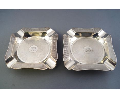 A pair of silver ashtrays of shaped cut corner form with all over engine turned decoration, Birmingham 1926, 11cm diameter, 1