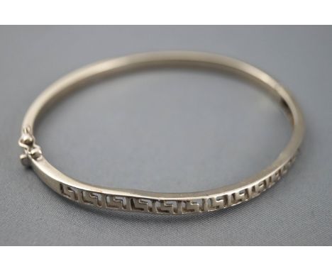 A white metal hinged bangle with cut out Greek key design. Push in clasp with figure of eight safety catch. No hallmark - aci