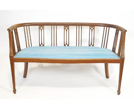 An Edwardian mahogany salon sofa with curved back rail, inlaid with chequered inlay over stick and splat motifs over a padded