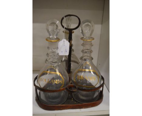 A decanter stand containing three decanters with stoppers, each with gilded decoration Hollands brandy and rum.