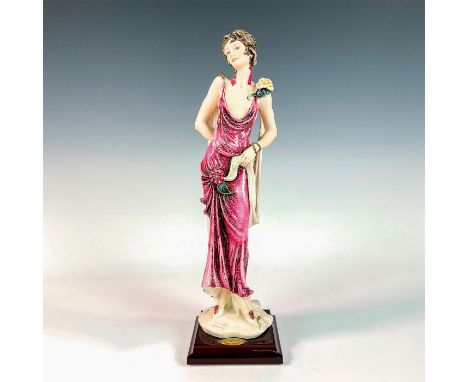 Matte and glossy finished figurine modeled as a 1920s styled woman wearing a revealing fuchsia colored gown with rose pin and