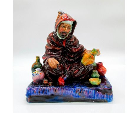 Glazed, hand painted Bone China figurine. Man wearing a brown cloak sitting on purple base with multicolored ceramics.Royal D