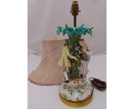 A Meissen style figural table lamp in the form of a man and lady standing under a tree mounted on gilded metal circular plint