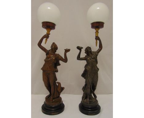 A pair of spelter figurine table lamp stands in the form of classical females, supporting torches with glass shades all on ra