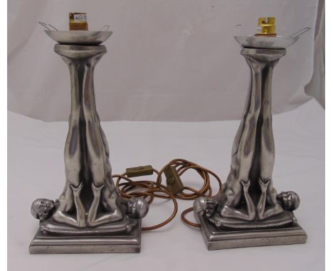 A pair of Art Deco style metal lamp stands in the form of naked flapper girls with raised legs on stepped rectangular bases, 