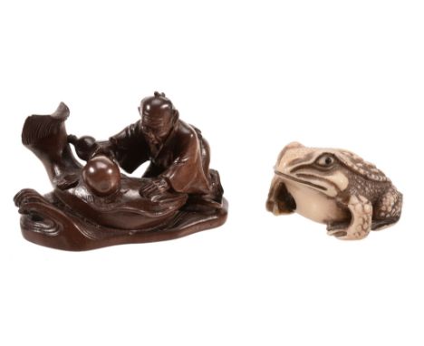 A Wood Okimono of a fisherman, kneeling beside a namazu whilst appearing to... A Wood Okimono of a fisherman, kneeling beside