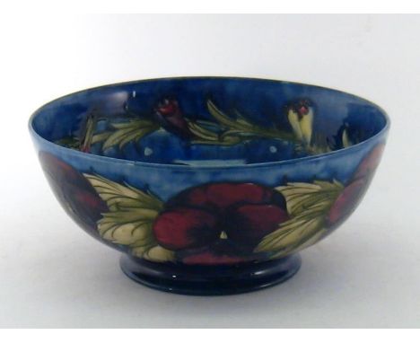 A large William Moorcroft ceramic fruit bowl in the pansy pattern on deep blue ground, the inside with a garland of opening p