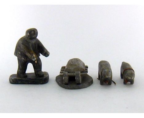 An Inuit carved soapstone group of a hunter with laden sled and two huskies with leather traces, the sled signed “DIMU”and da