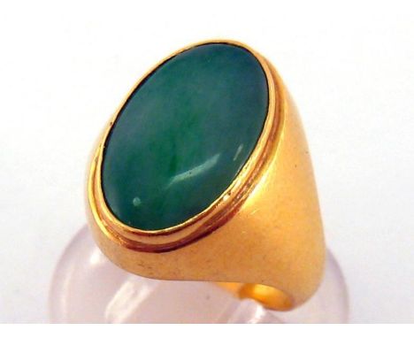 A jade ring, the oval jade tablet 14.5 x 9.5mm, rub over set, mounted in yellow metal (tests 18 carat gold), obscure marks, f