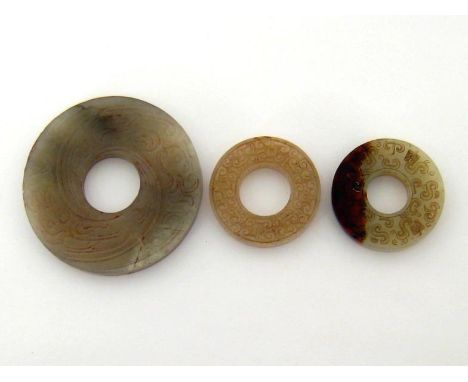 Three Chinese jade bi, the largest grey jade carved on both sides with a phoenix around, the other two, one white, one celado