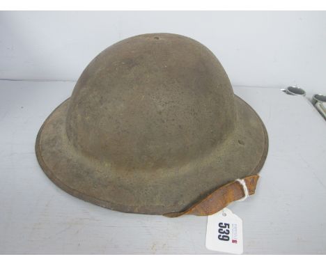 A WWI British Army Brodie Steel Combat Helmet, with textured paint finish, includes liner and chin strap, manufacturer mark H