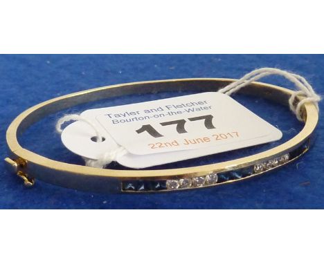 A ladies 20th Century 14 carat yellow gold Bangle channel set with eight round brilliant cut diamonds and nine cushion cut sa