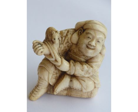 A 19th Century carved Japanese ivory Netsuke, modelled as a seated smiling character, a rat perched upon the sleeve of his ou