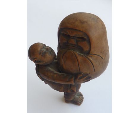 A 19th Century carved Japanese patinated wooden Netsuke modelled as a young boy (with articulated head) looking up and carryi