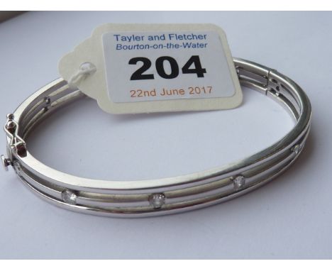 A heavy 18 carat white gold Bangle set with thirteen diamonds 