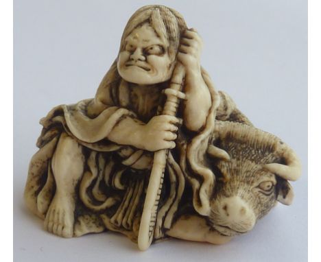 A 19th Century carved Japanese ivory Netsuke modelled as a Samurai with katana sword and seated upon the back of a recumbent 