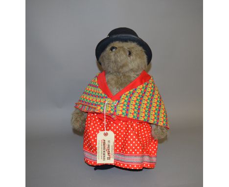 Gabrielle Designs Paddington Bear Aunt Lucy, wearing black hat, colourful shawl, red polkadot skirt and bloomers, money insid