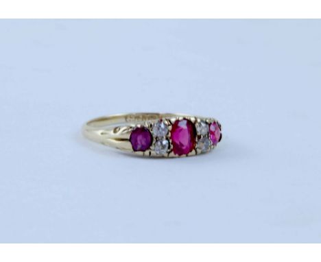 An 18ct gold multi-stone ring with central ruby-coloured stone flanked by a pair of diamond chips and a further ruby-coloured