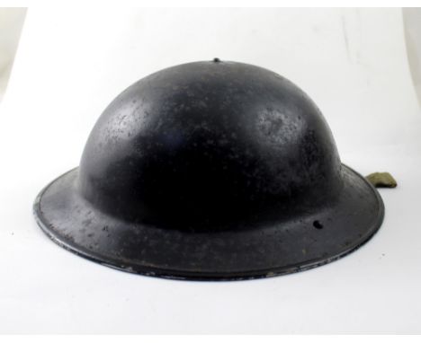A WWII steel helmet painted black with original insert and webbing chin strap, stamped 1941.