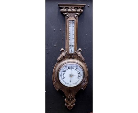 A 1920s barometer/thermometer on carved floral oak mount, height 90cm. CONDITION REPORT Please note that this lot is not suit