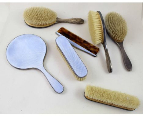 A hallmarked silver and enamelled dressing table set comprising two clothes bushes, three hand brushes, a comb and a hand mir