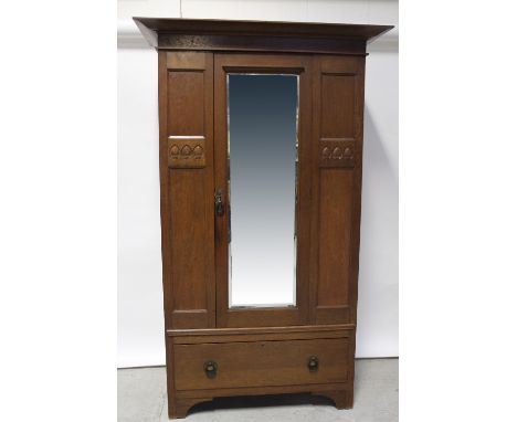 An Arts &amp; Crafts oak wardrobe, mirrored door over single drawer with carved stylised leaf motifs, on bracket feet, height